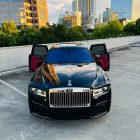 Front view of a black 2021 Rolls-Royce Ghost sedan with both front doors open, parked in an outdoor lot.