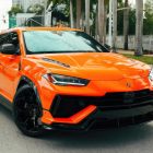 Bright orange Lamborghini Urus Performante SUV parked on a city street.